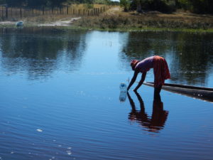 A lady collects drinking water from the river.